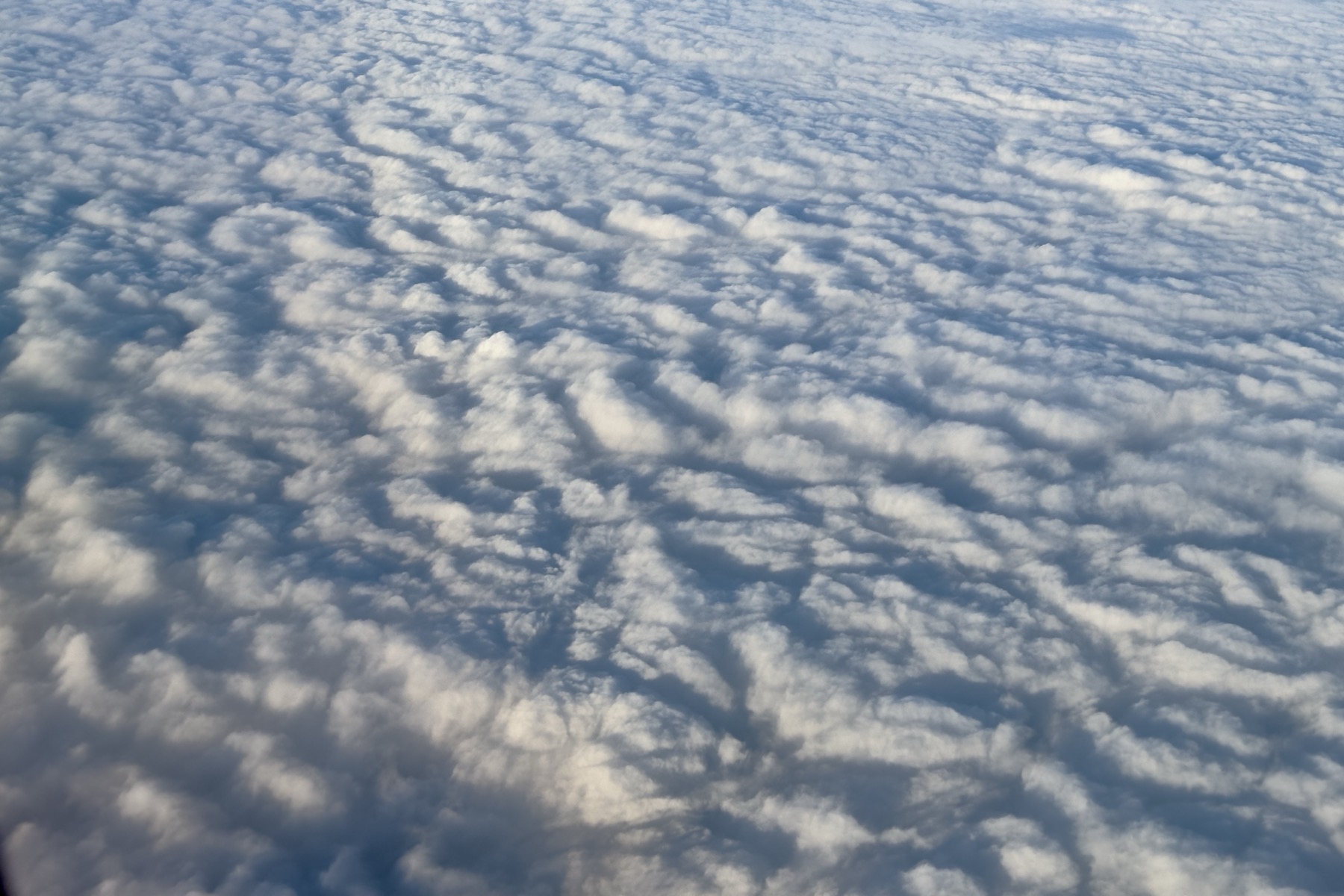 Looking down on a bed of clouds from 35000 feet. They riffle like water.