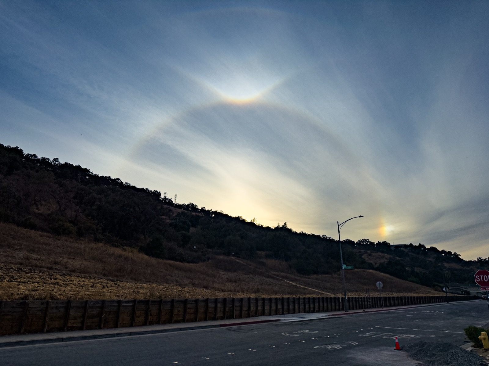 Quite a few optical phenomena decorating the setting sun that is just hidden behind the hill.