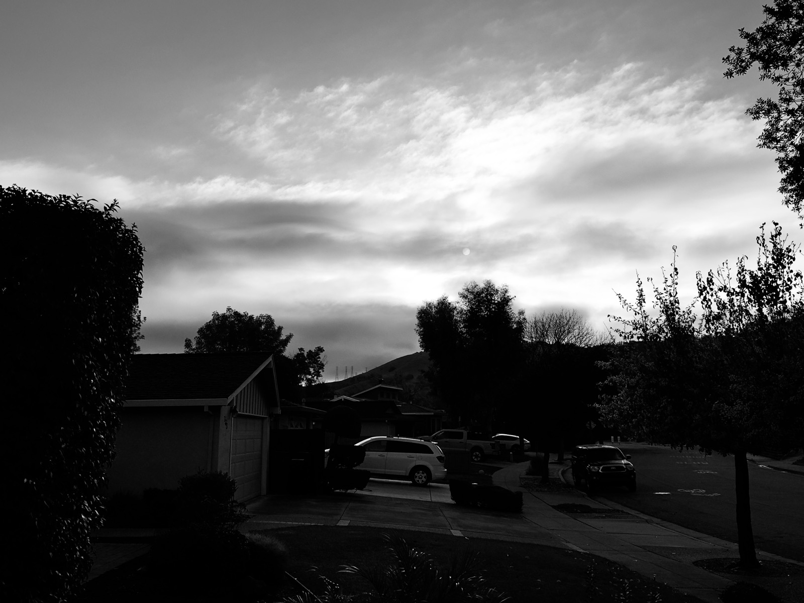 The sun through clouds over a suburban street.